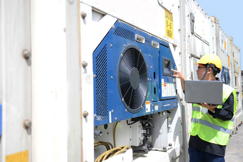 A reefer container technician monitors temperature